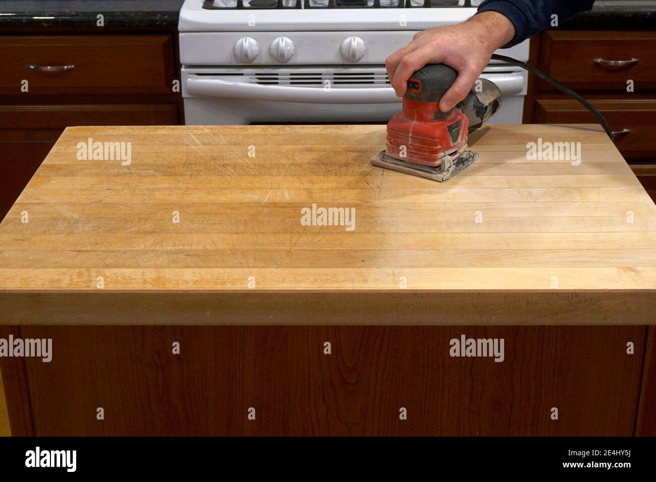Rifinitura di un banco da cucina con una smerigliatrice elettrica Foto Stock
