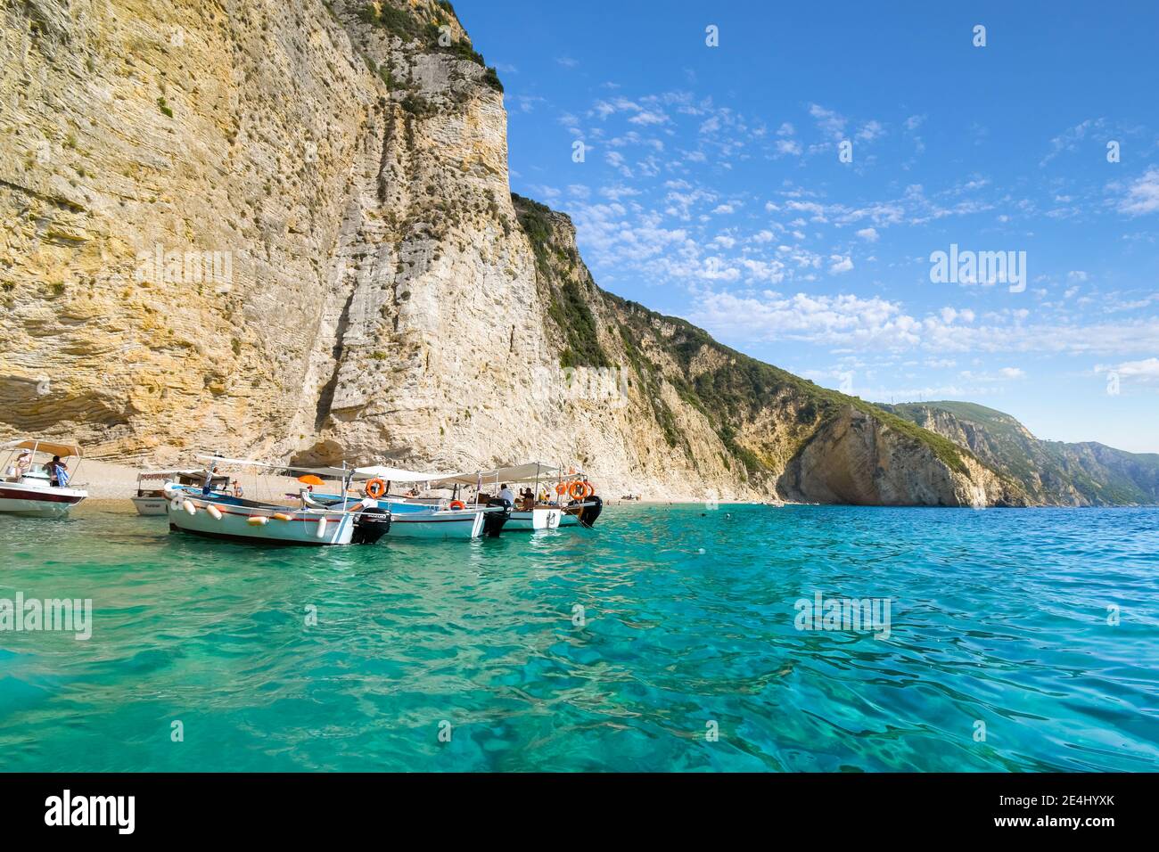Barche di linea fino al litorale nelle limpide acque fuori dalla sabbiosa spiaggia Paradiso o Chomi Beach in una giornata di sole a Corfu Grecia. Foto Stock