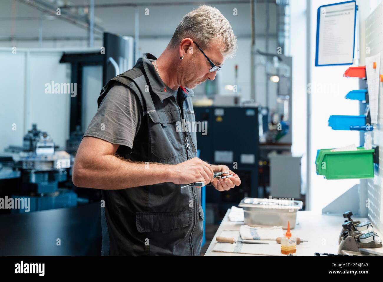 Ingegnere maturo che lavora con l'utensile manuale mentre si trova in azienda Foto Stock