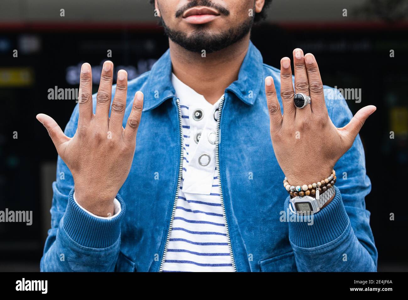Primo piano di hippie uomo mid adult con giacca blu che mostra mani Foto Stock