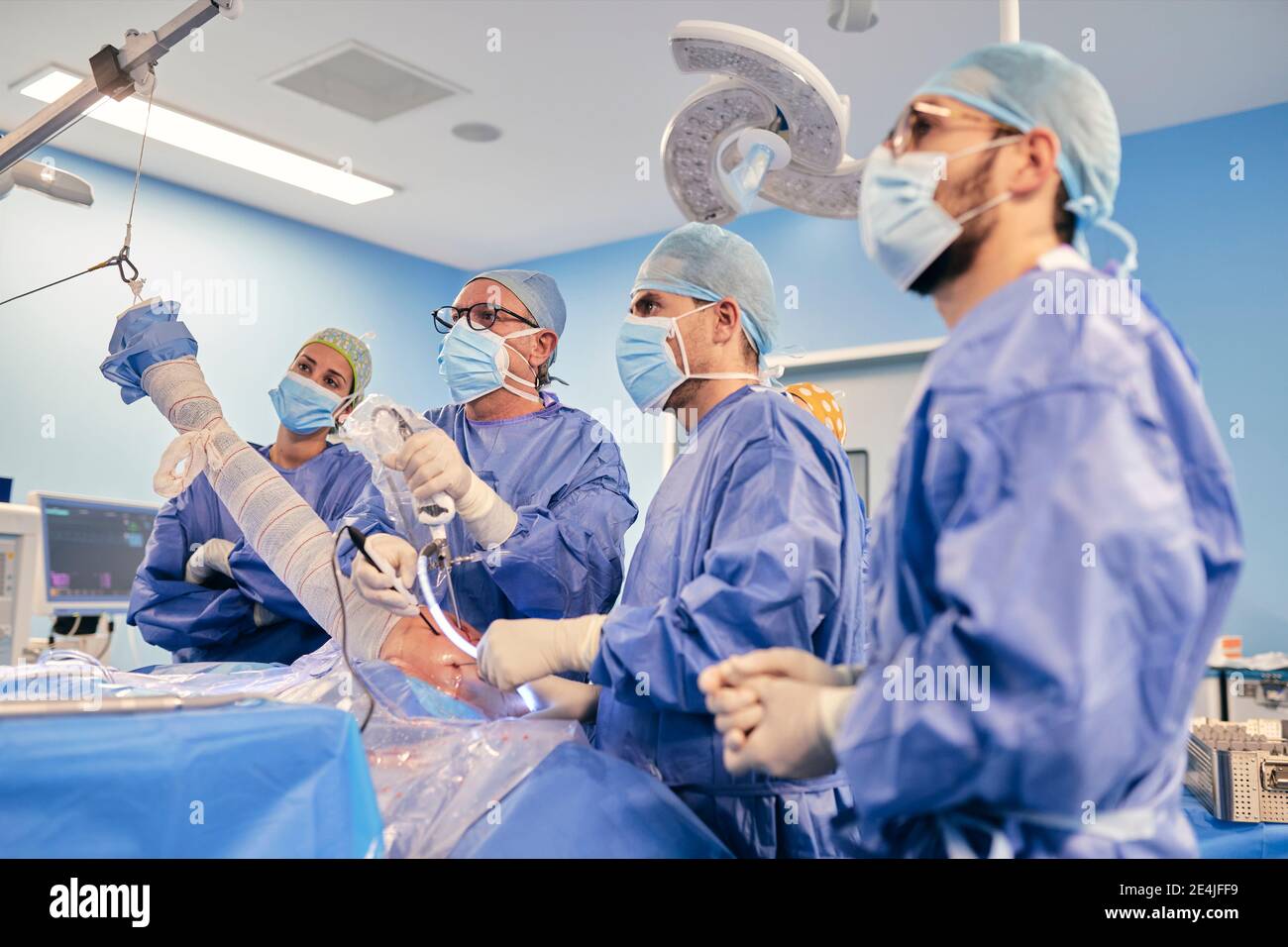 Chirurgo con apparecchiatura endoscopica che opera artroscopia della spalla mentre in piedi con Collega in sala operatoria durante il COVID-19 Foto Stock