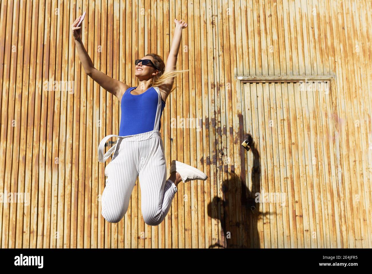 Ragazza che salta mentre fa un selfie con il suo smartphone. Foto Stock