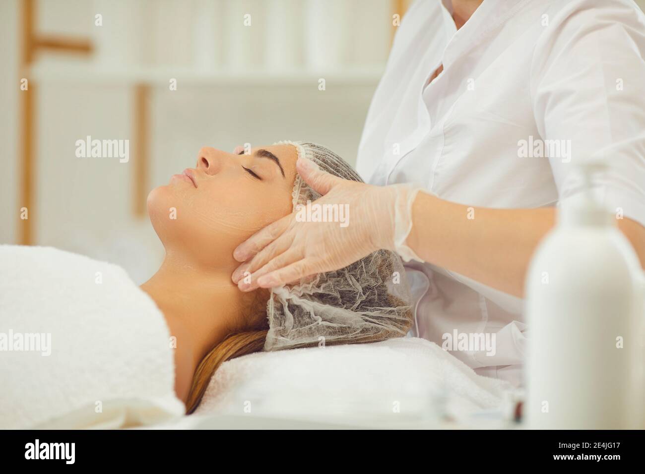 Mani di massaggiatore che fanno massaggio facciale di sollevamento per la donna giovane Foto Stock