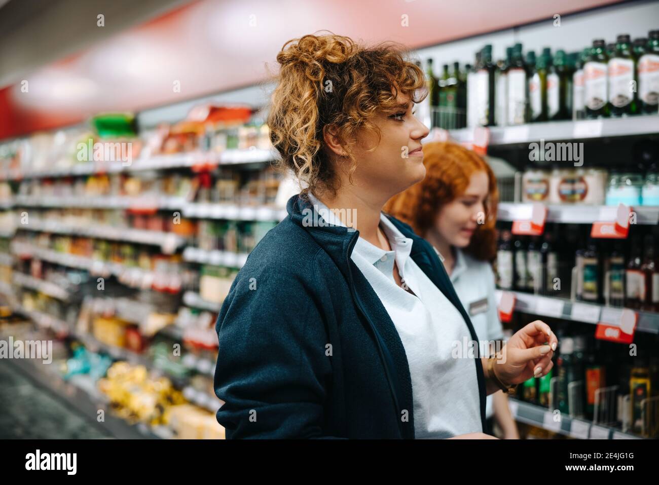 Donna che cammina con una collega al supermercato. Responsabile del negozio di alimentari che guarda i rack da esposizione. Foto Stock