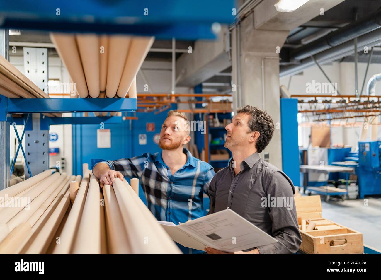 Due falegnami che esaminano i pali di legno nella sala di produzione Foto Stock