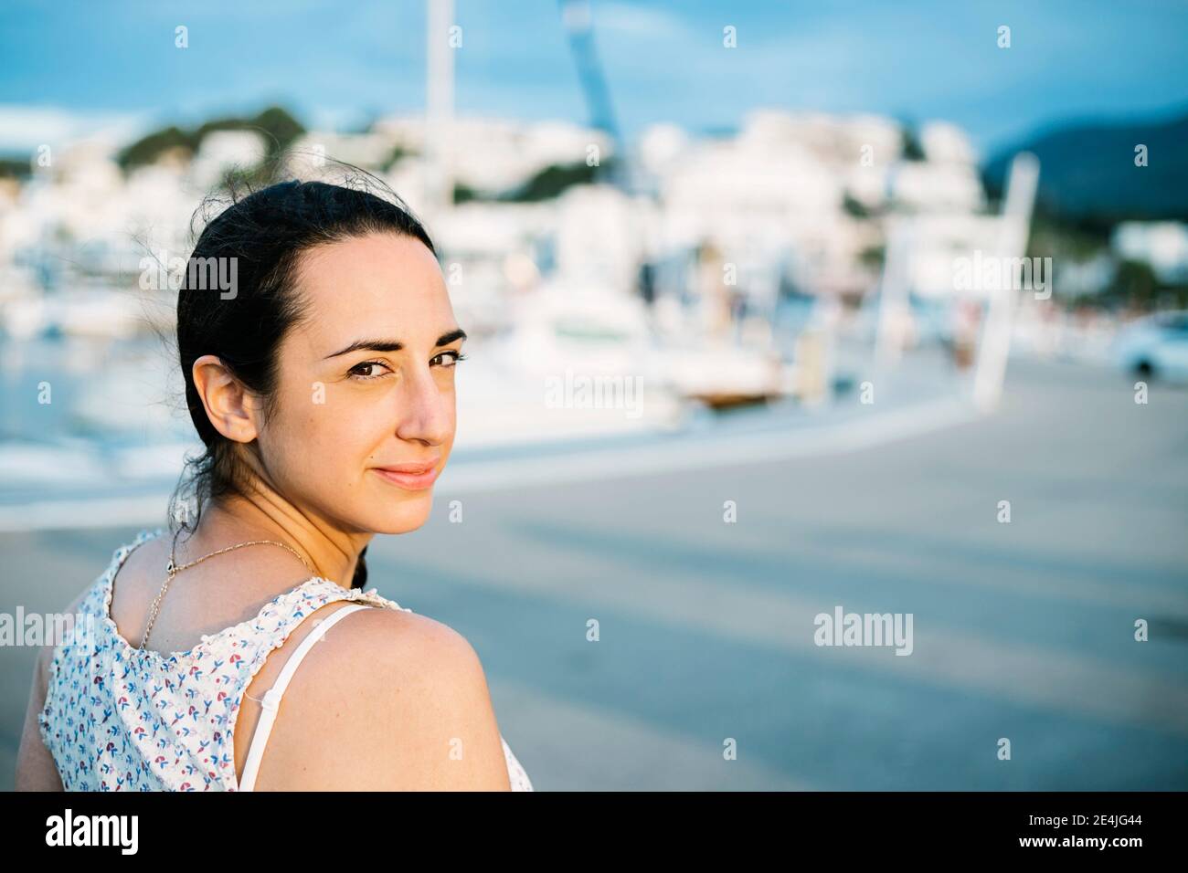 Donna sorridente in città al tramonto Foto Stock