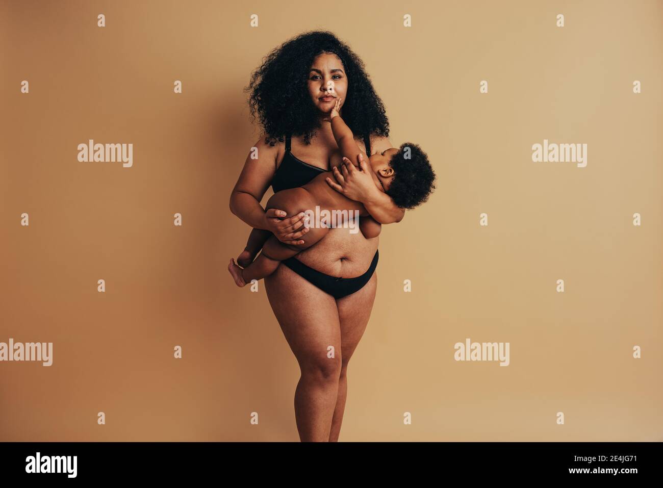Più taglia donna che allatta il suo bambino. Madre con il bambino in piedi e allattando al seno. Foto Stock