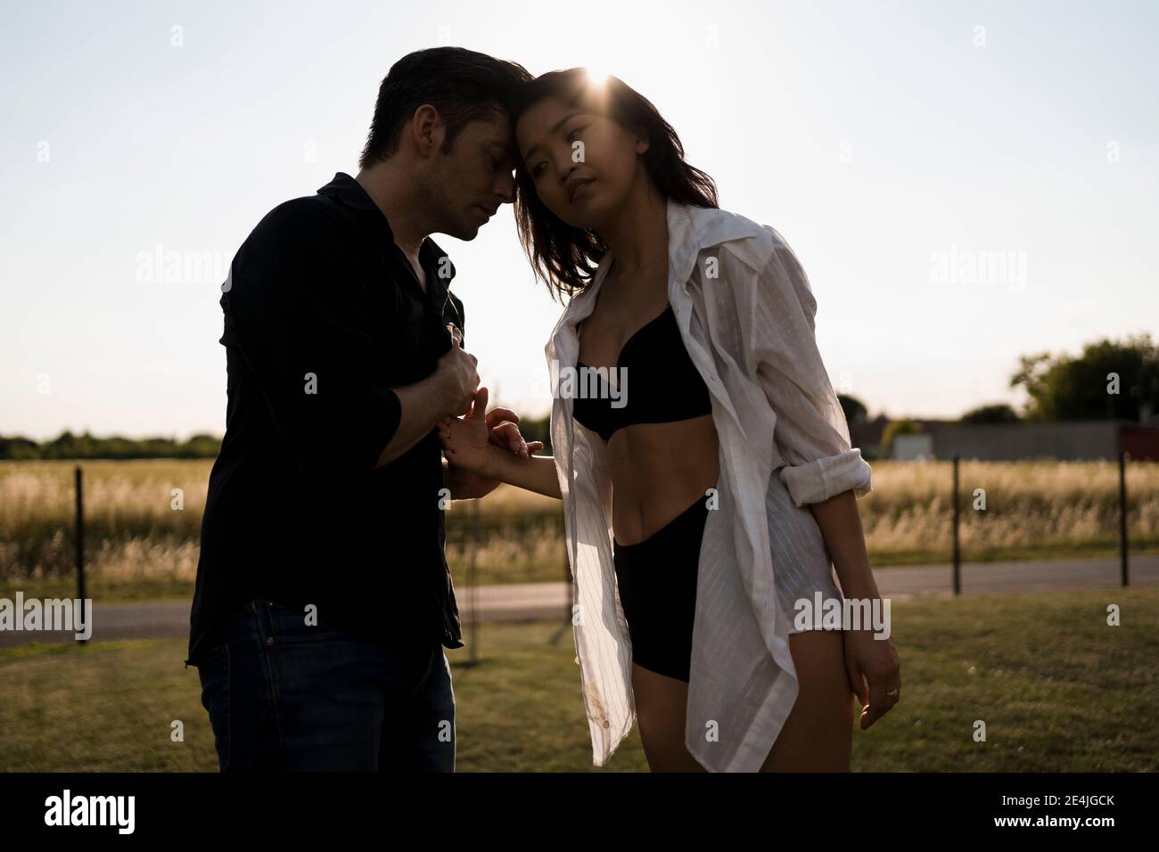 Coppia di ballerini eterosessuali affettuosi che tengono la mano in campo il giorno di sole Foto Stock