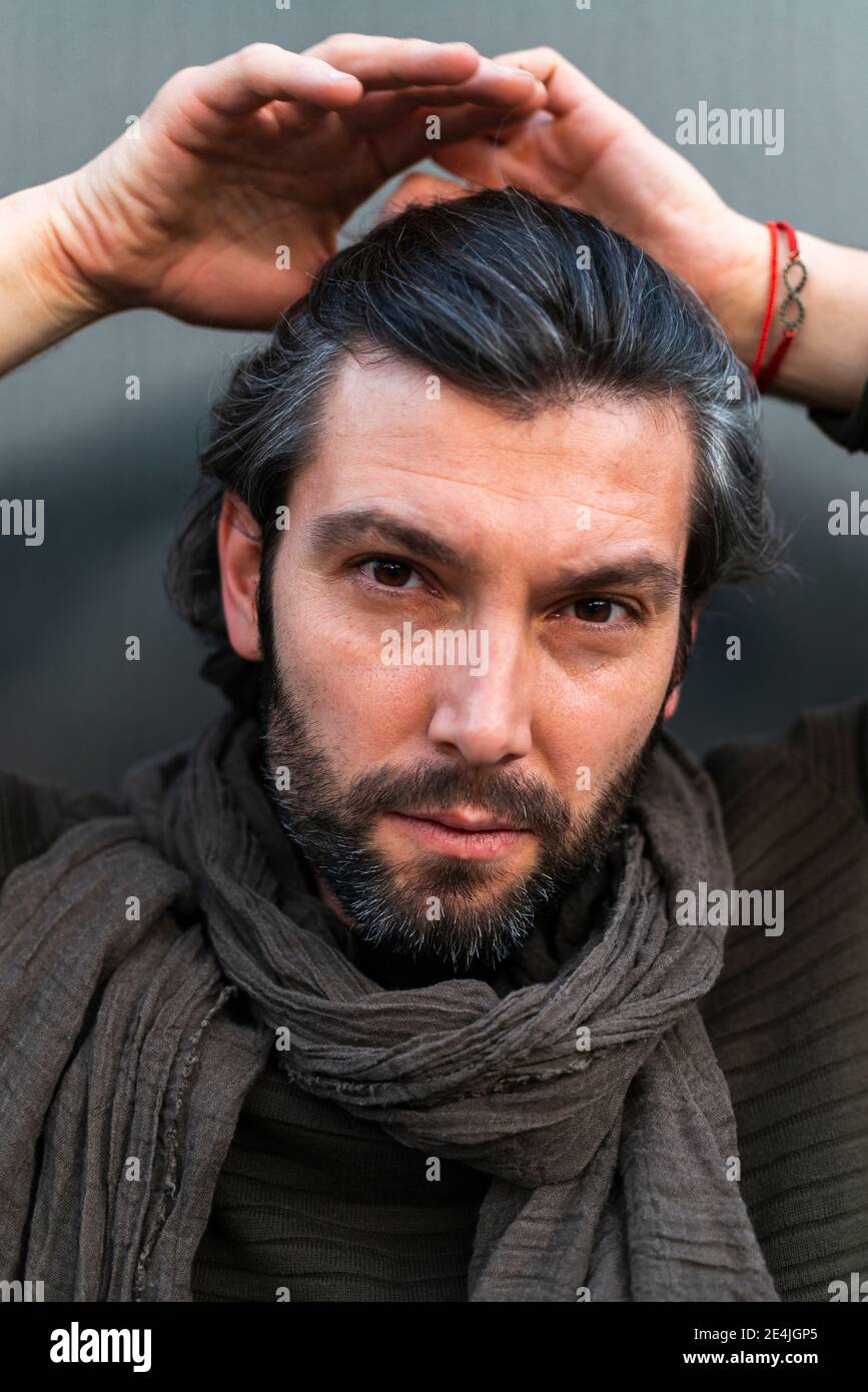 Ritratto di uomo che indossa sciarpa di fronte al muro grigio Foto Stock