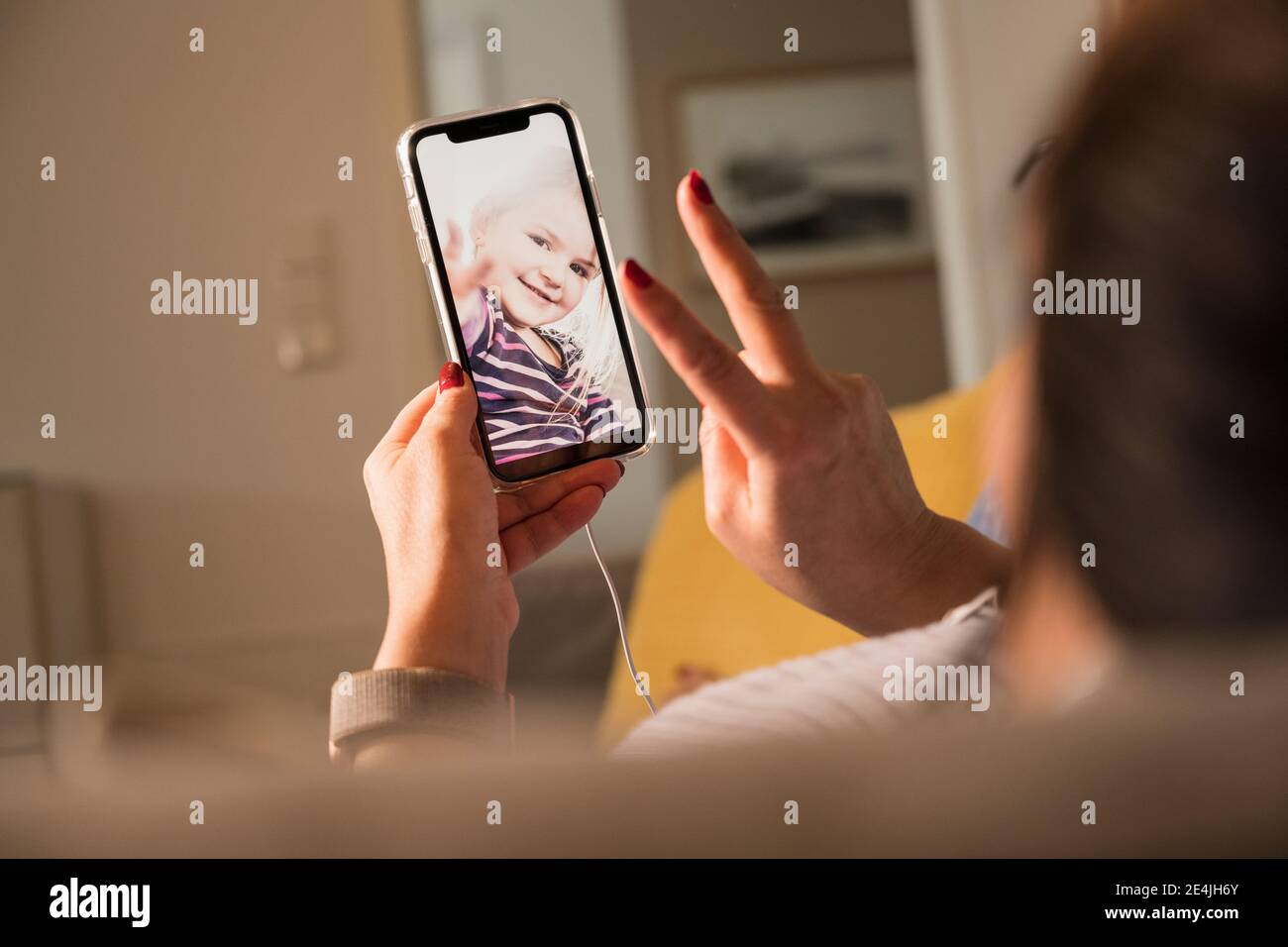 Madre che mostra il segno di pace a figlia in video chat a. casa Foto Stock
