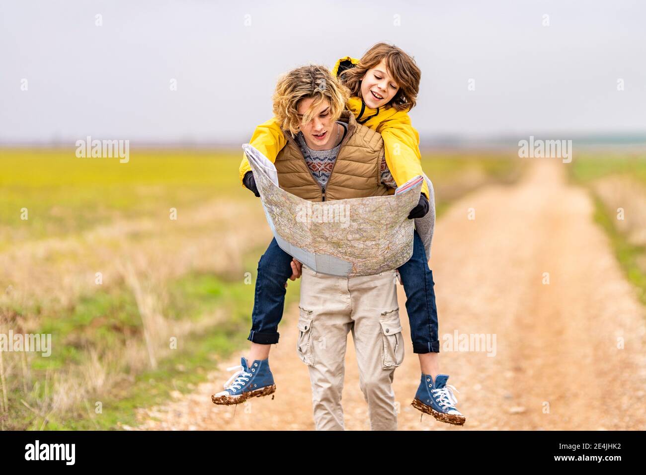 Giovane uomo piggybacking fratello più giovane durante l'escursione Foto Stock