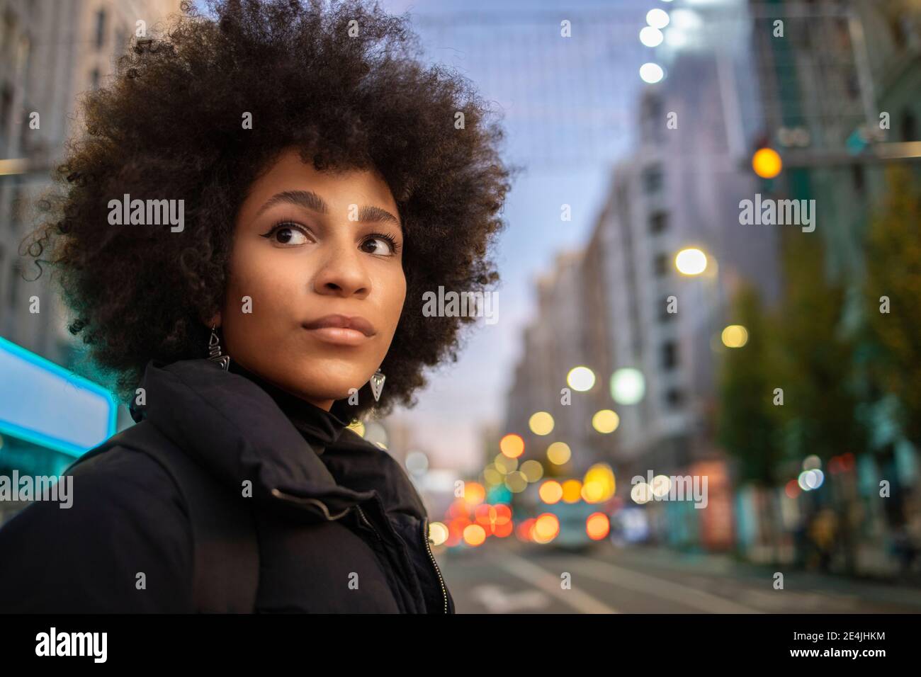 Giovane donna che contempla mentre sta in città di notte Foto Stock