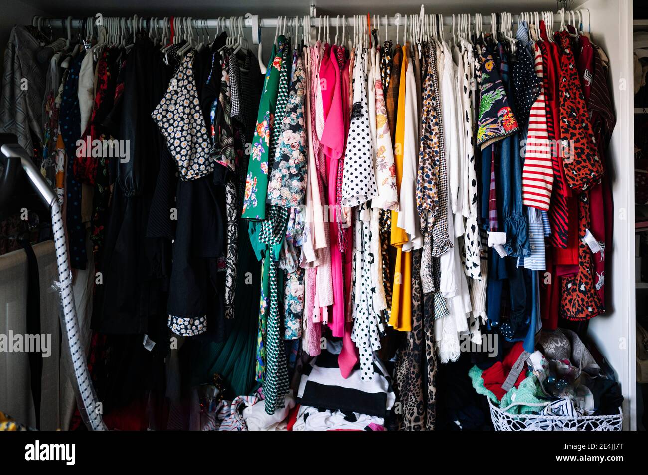 Variazione di vestiti appesi su scaffale in armadio in appartamento Foto Stock