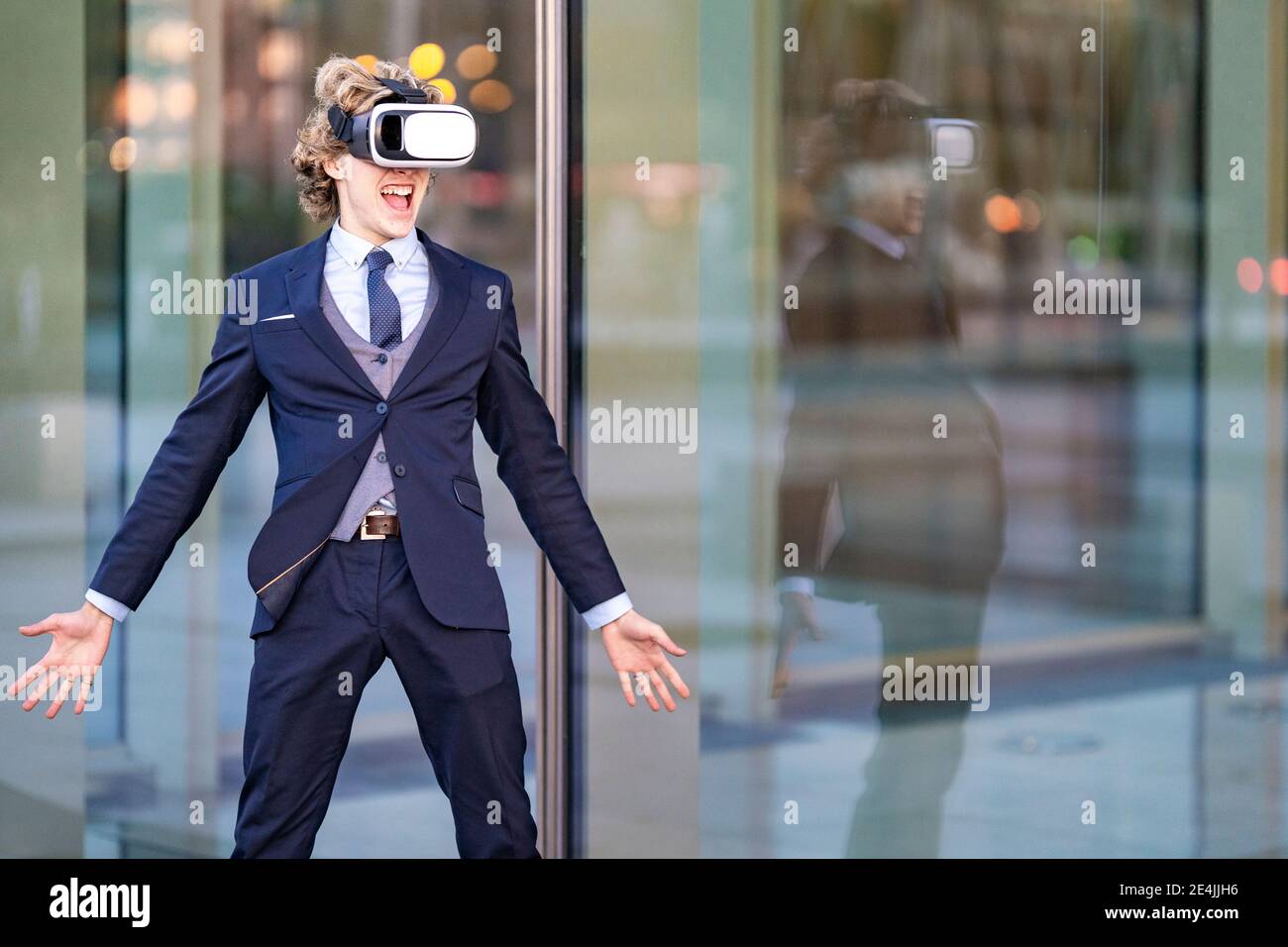 Eccitato imprenditore maschio urlando mentre indossa VR Box contro l'ufficio edificio Foto Stock