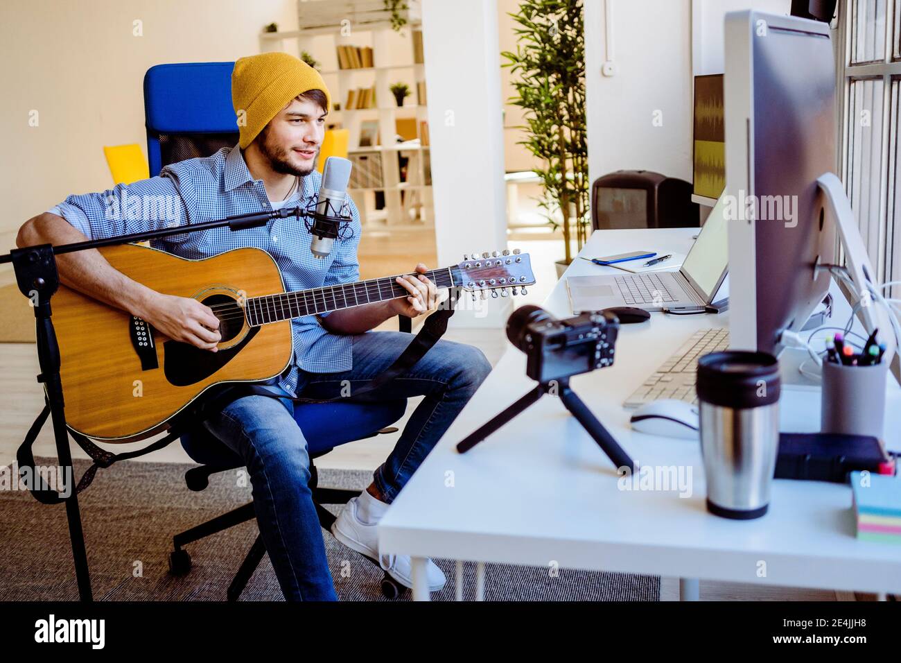 Musicista che insegna a suonare la chitarra sulla macchina fotografica mentre si siede a. studio di registrazione Foto Stock