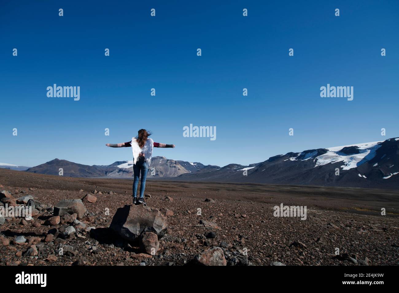 Ragazza che indossa ali artificiali in piedi con braccia estese contro chiaro cielo Foto Stock