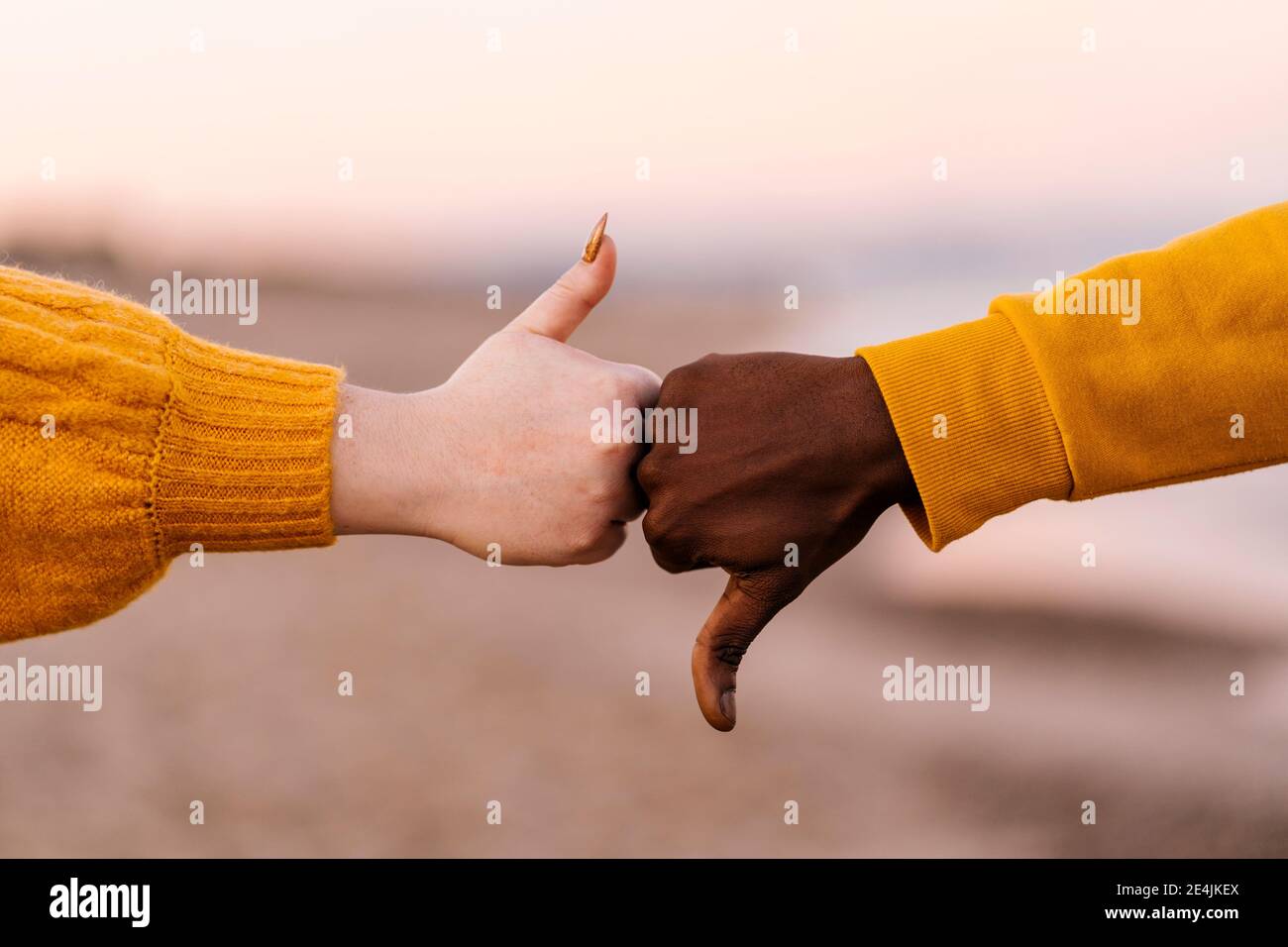 Uomo e donna che gesturing con i pollici su e giù a. spiaggia Foto Stock