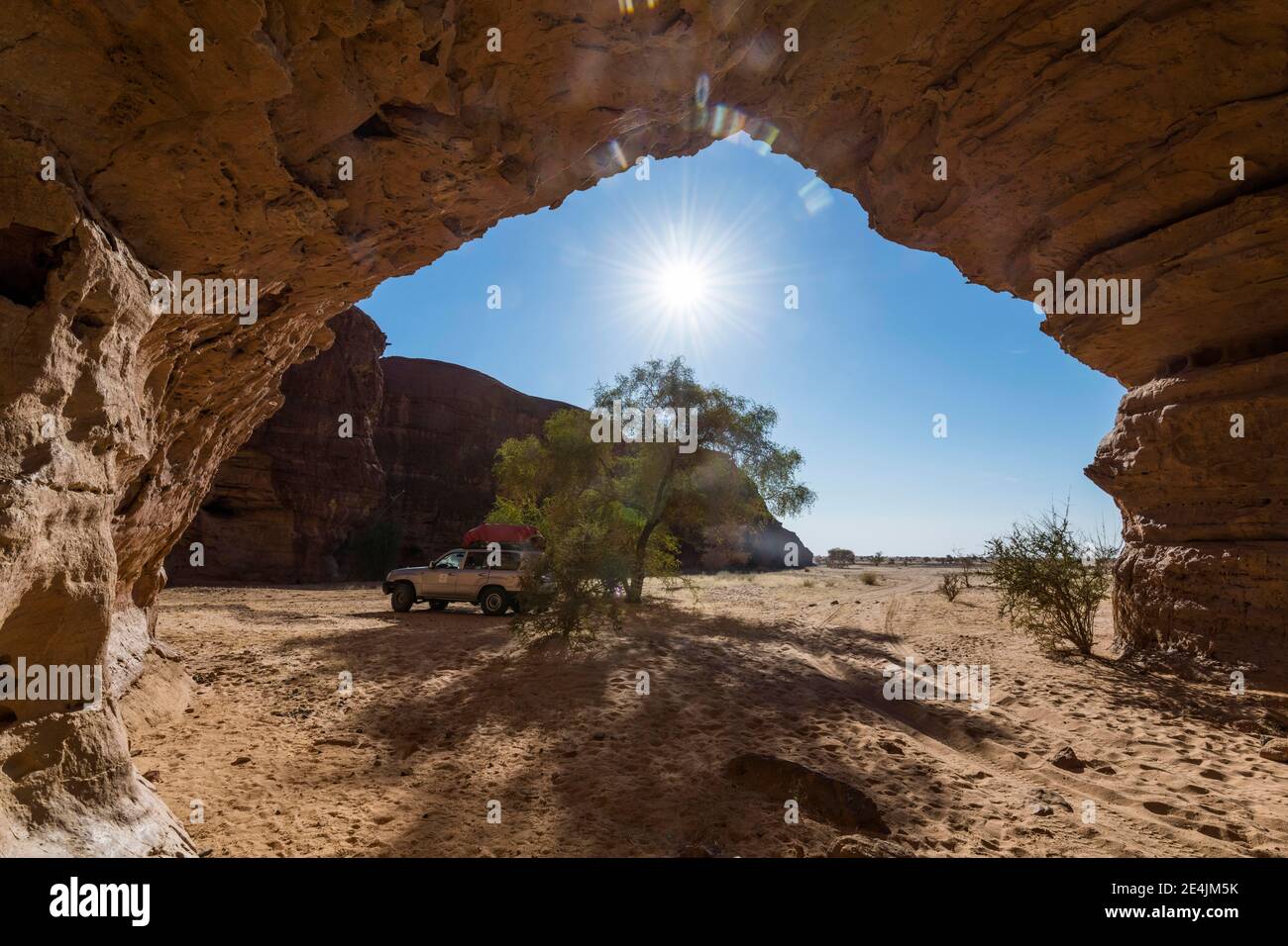 Veicolo fuoristrada sotto l'arco roccioso, altopiano di Ennedi, Ciad Foto Stock