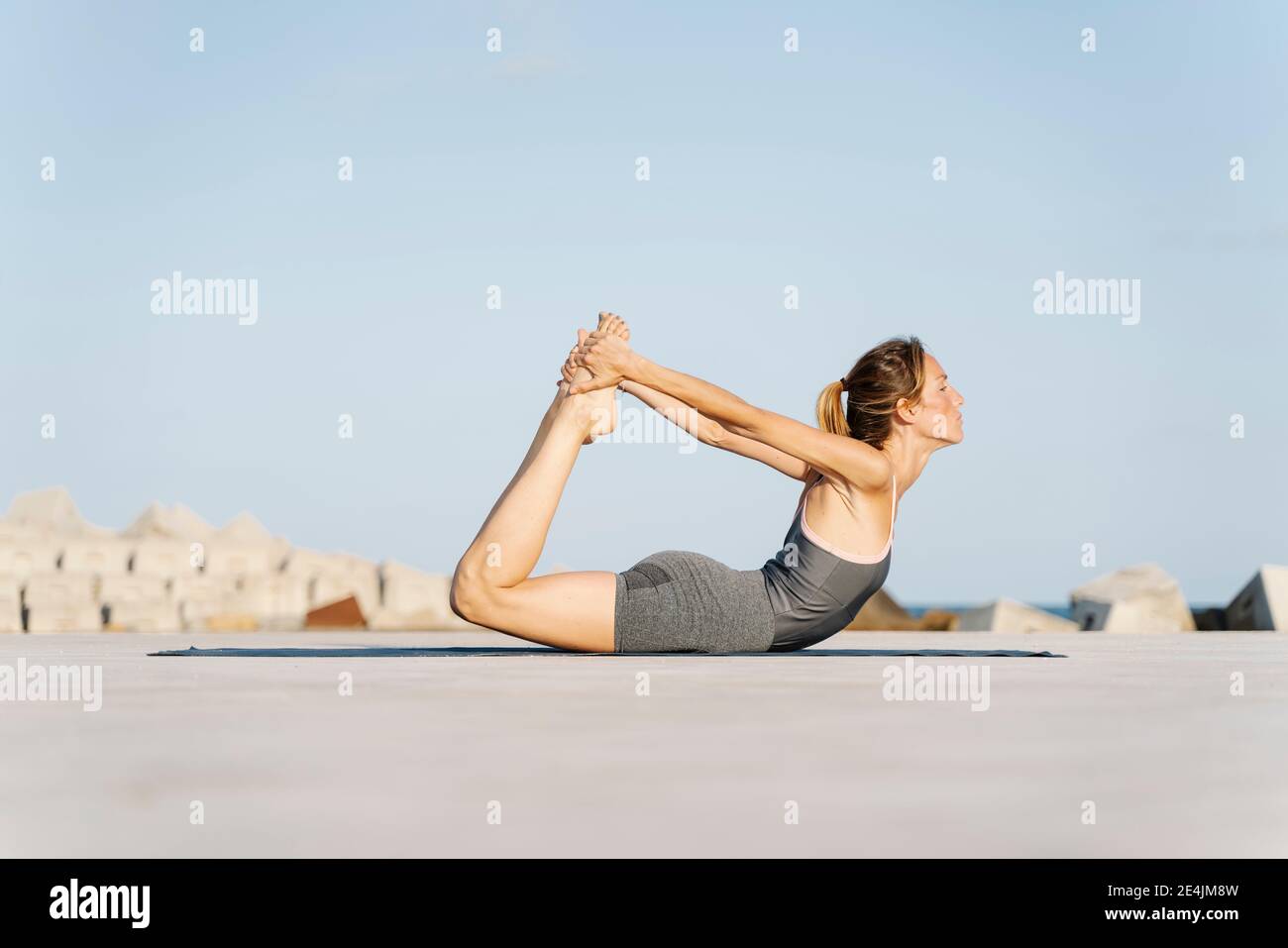 Sport swoman che fa posa di arco in giorno di sole Foto Stock