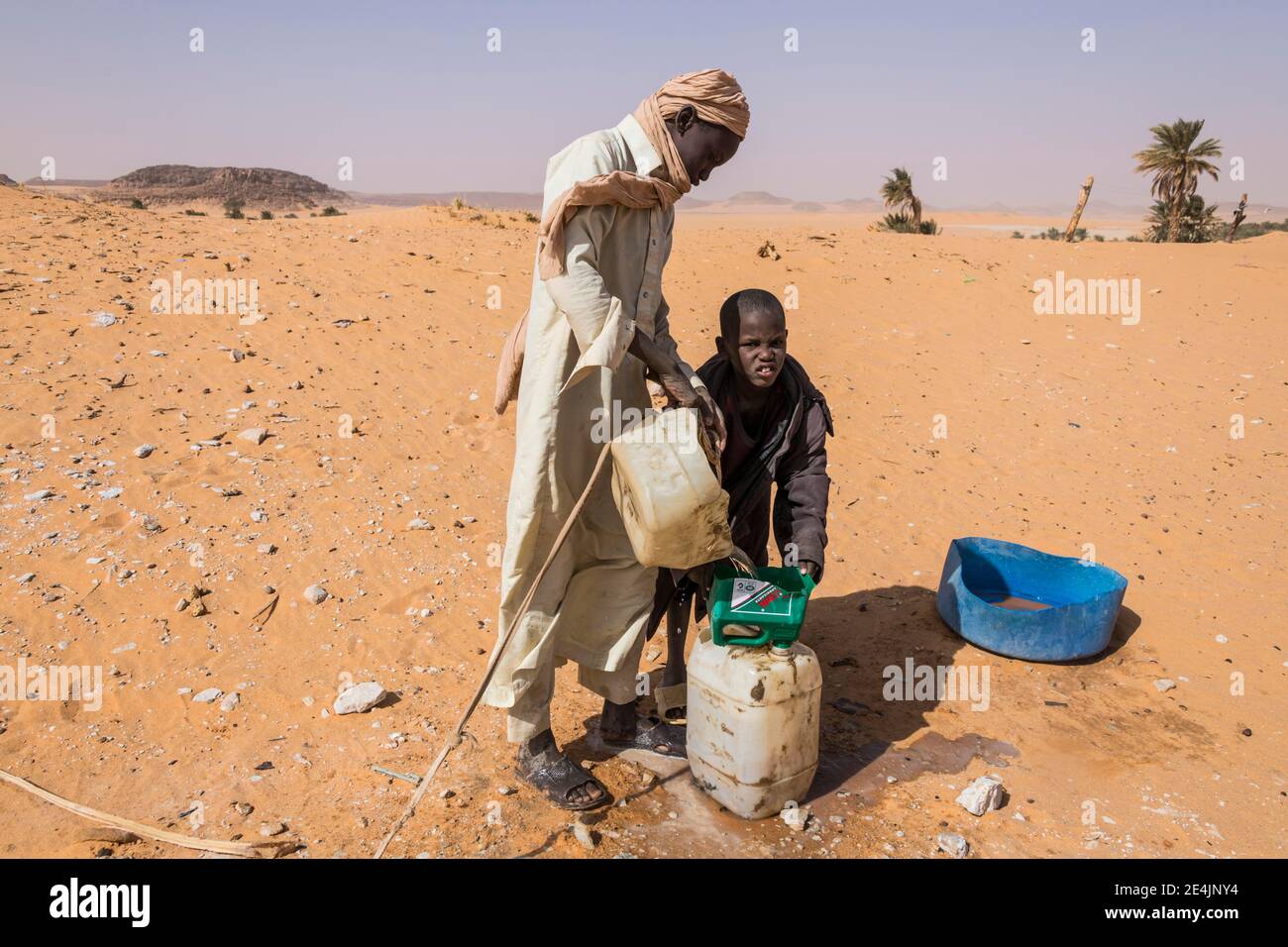 Ragazzi locali che tirano fuori l'acqua da un pozzo nel deserto, Sahara tra Ounianga Kebir e Faya, Ciad Foto Stock