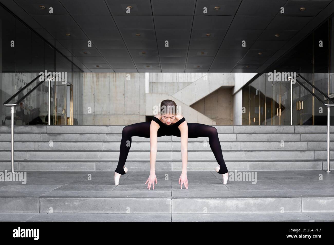 Ballerina in nero leotard in un moderno edificio in cemento Foto Stock