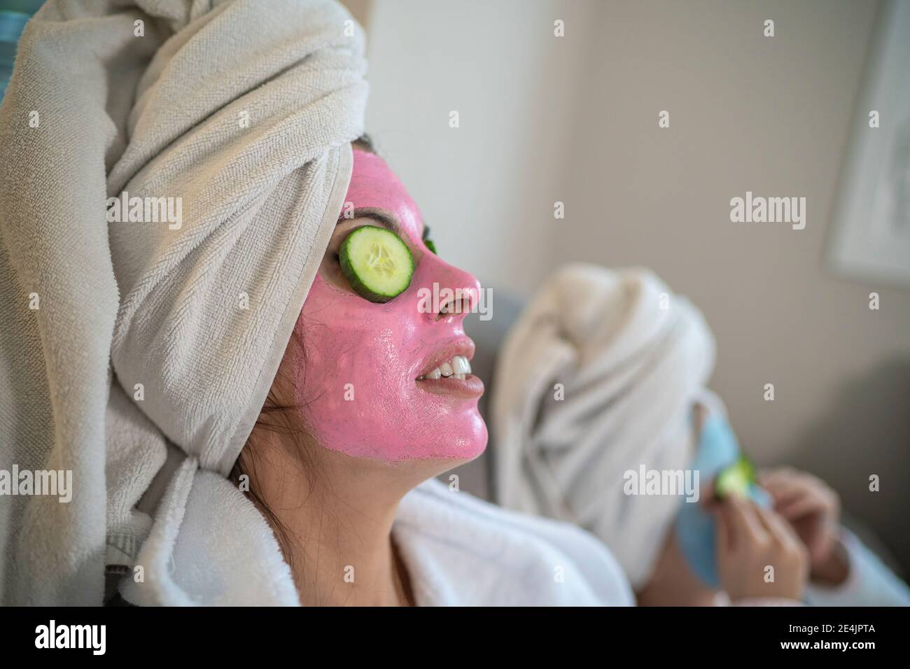 Madre e figlia con maschere facciali che si rilassano a casa Foto Stock