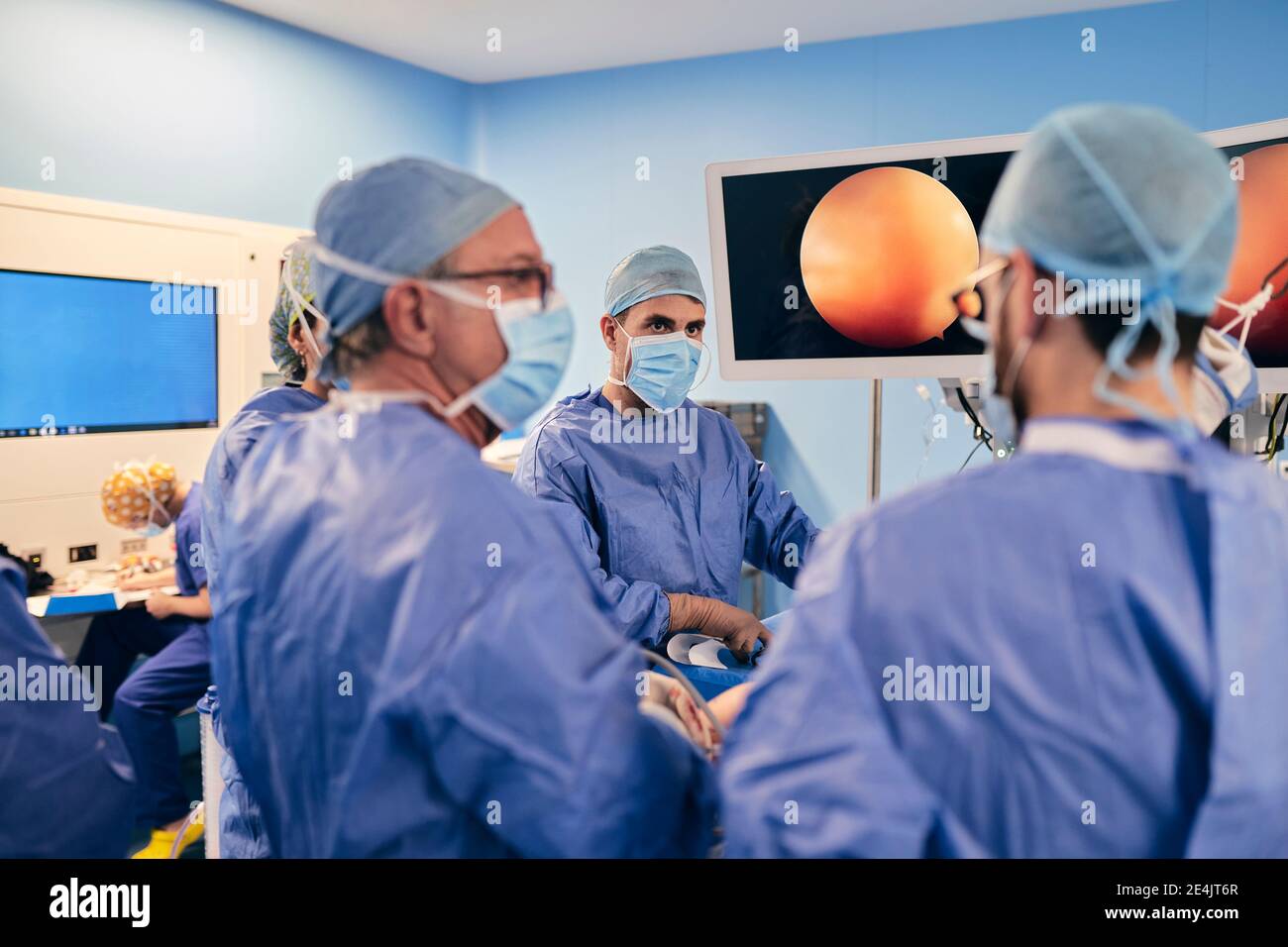 Chirurghi che indossano la maschera di faccia che hanno discussione mentre operating la chirurgia dentro sala operatoria Foto Stock