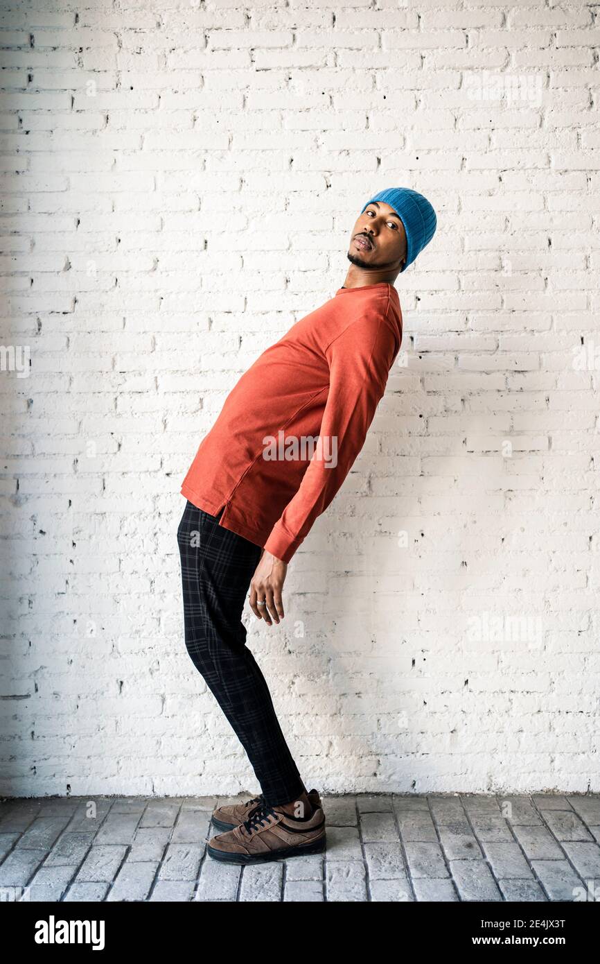 Uomo medio adulto che si piega di nuovo contro muro bianco di mattoni Foto Stock