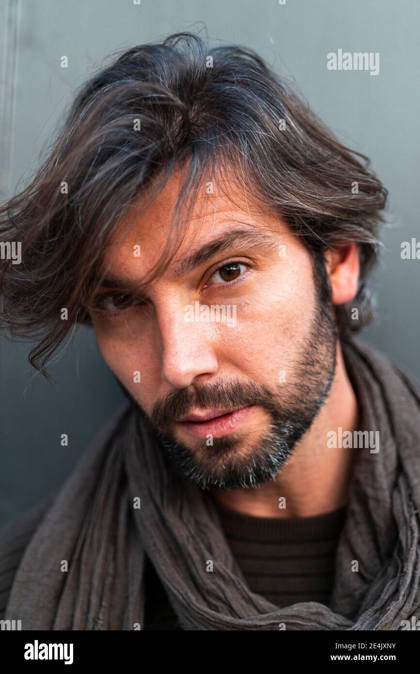 Ritratto di uomo che indossa sciarpa di fronte al muro grigio Foto Stock