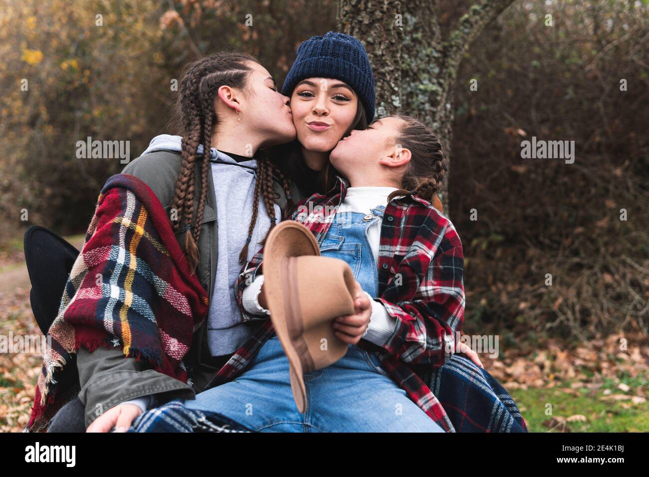 Due ragazze che baciano la sorella nel paesaggio autunnale Foto Stock