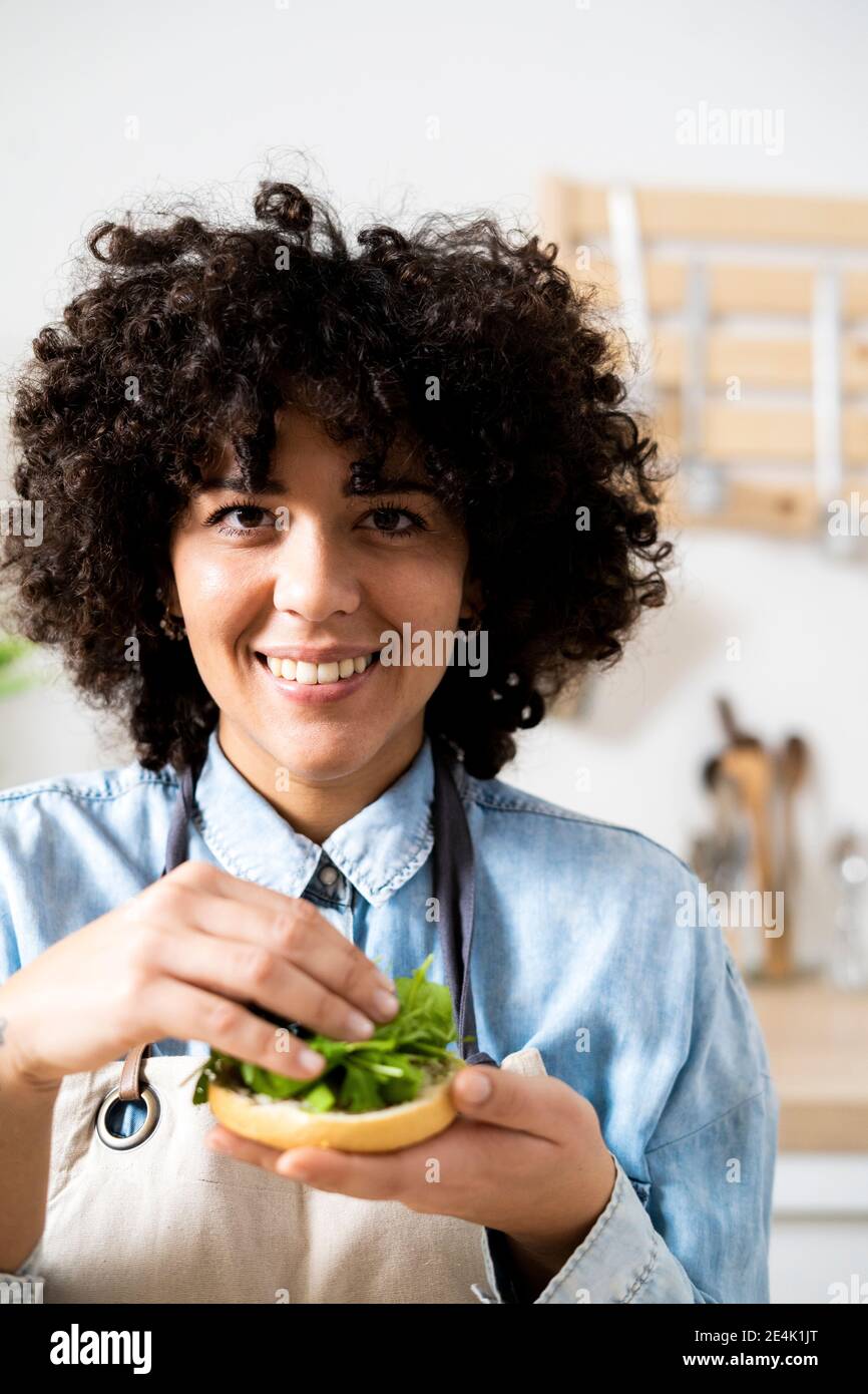 Ritratto di giovane donna sorridente mentre si preparano panini vegani con rucola Foto Stock
