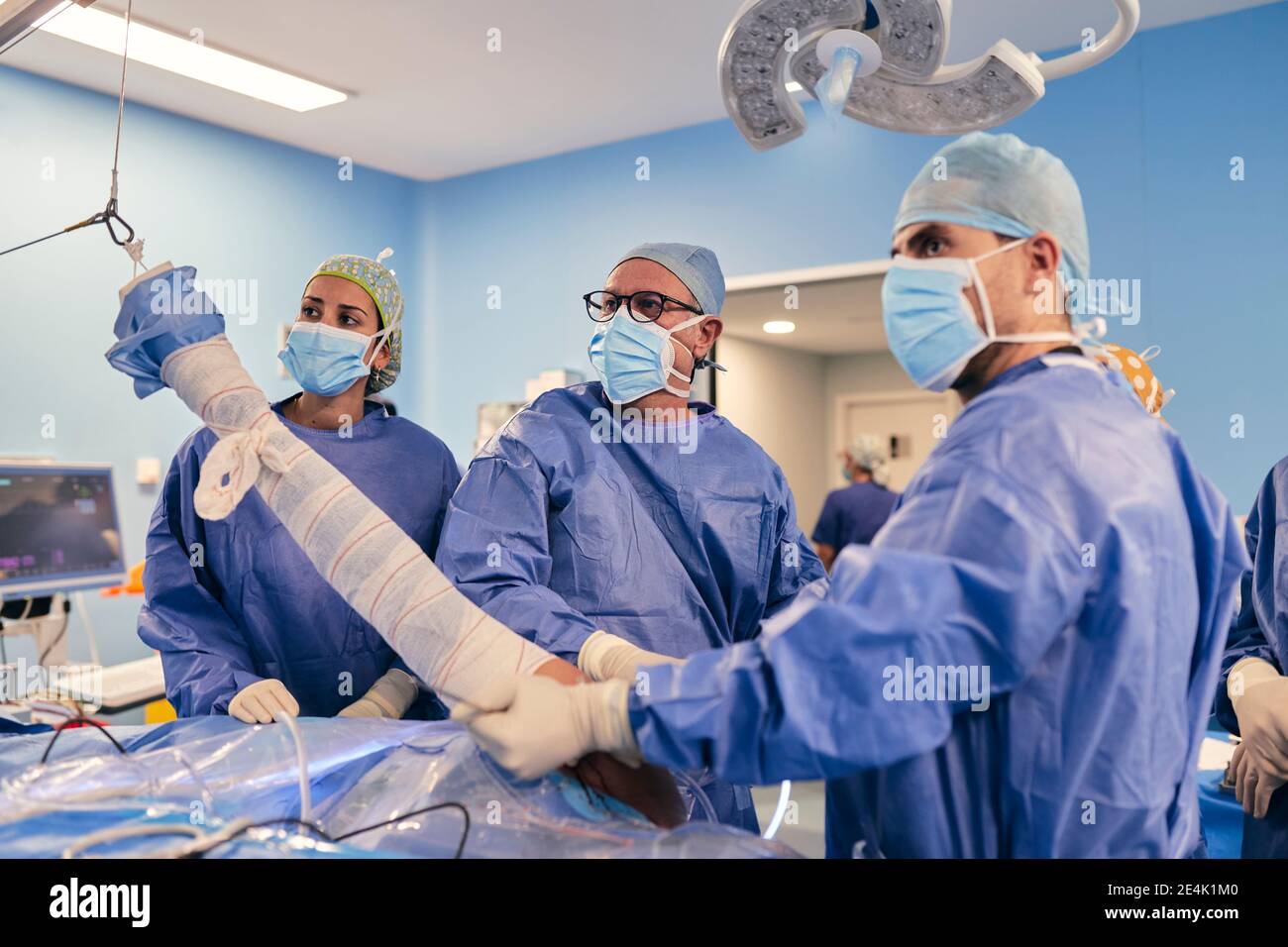 I medici che indossano la maschera protettiva di intervento chirurgico mentre si è in piedi sala operatoria Foto Stock