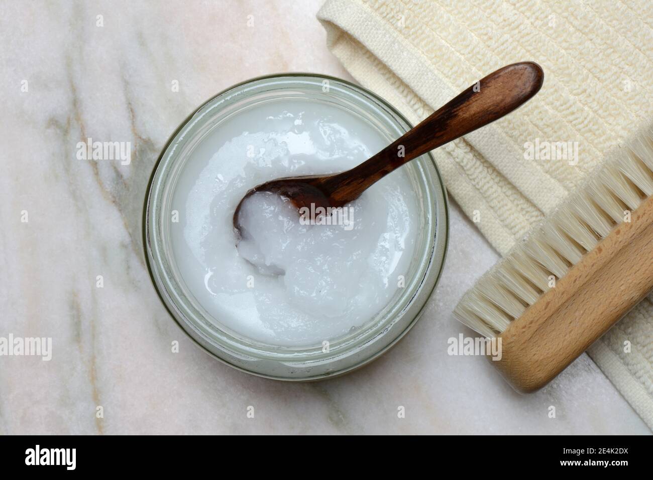 Olio di cocco con cucchiaio di legno, asciugamano con spazzola Foto Stock