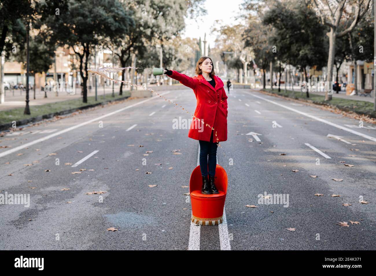 La giovane donna si affida in tasche versando il caffè mentre si sta in piedi sedia su strada Foto Stock