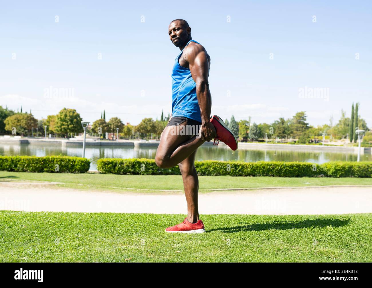 Sportivo che fa esercizio con le gambe nel parco durante la giornata di sole Foto Stock