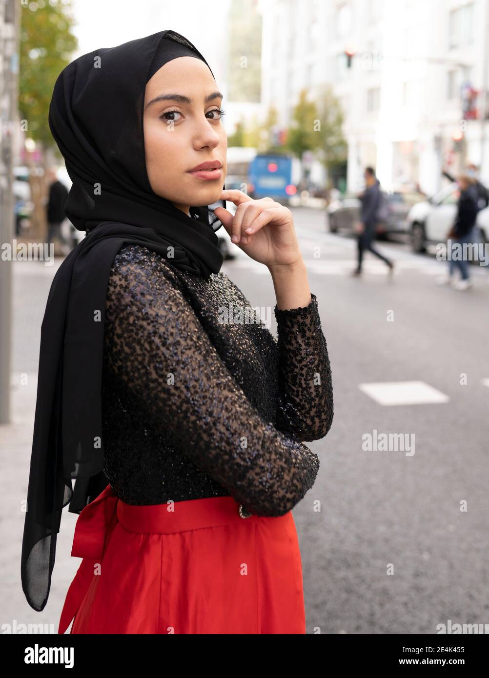 Ritratto di giovane bella donna che indossa hijab nero in posa via della città Foto Stock