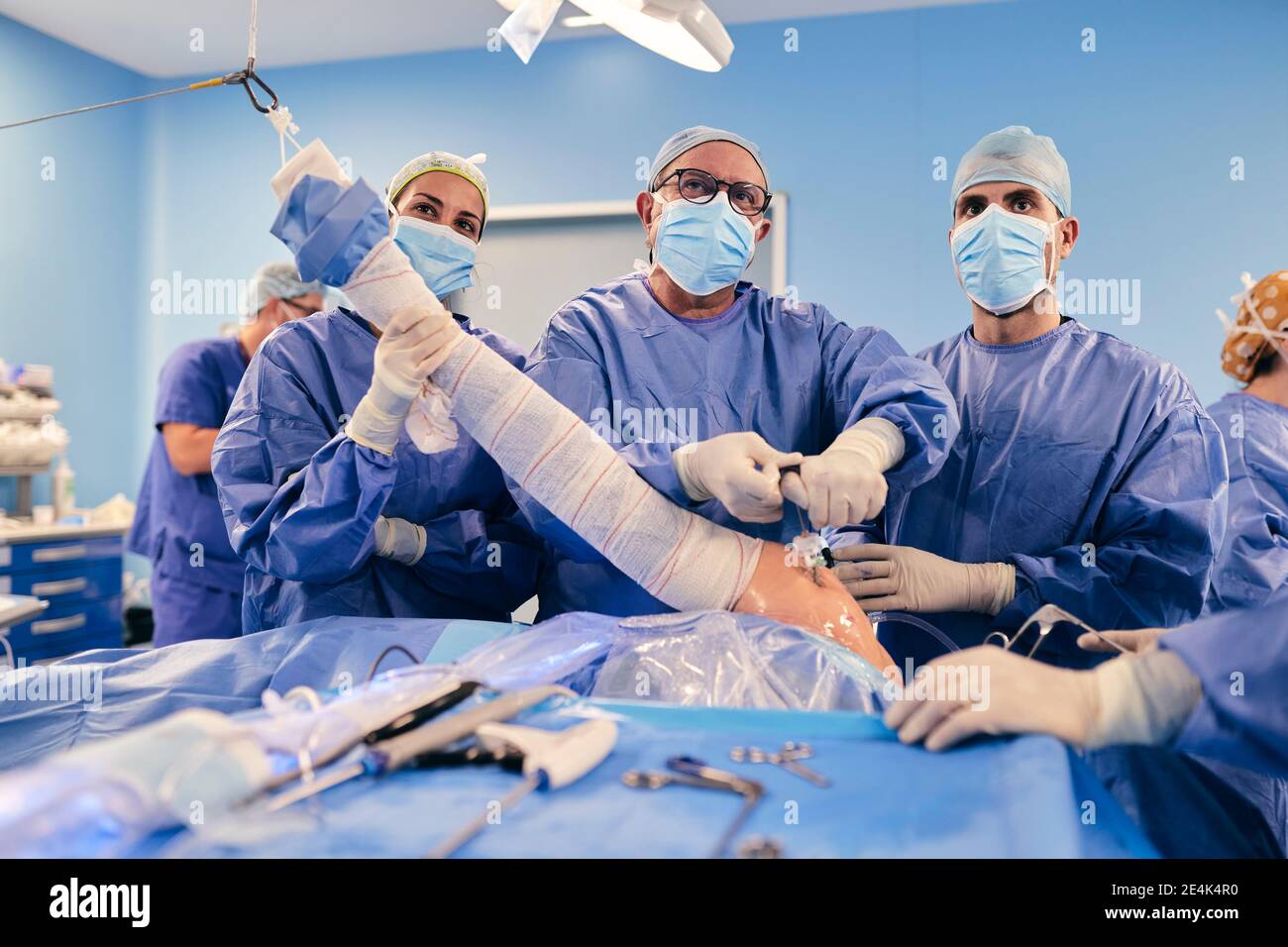 Medici squadra con l'apparecchiatura dell'endoscopio che funziona chirurgia artroscopica della spalla in Sala operatoria durante il COVID-19 Foto Stock