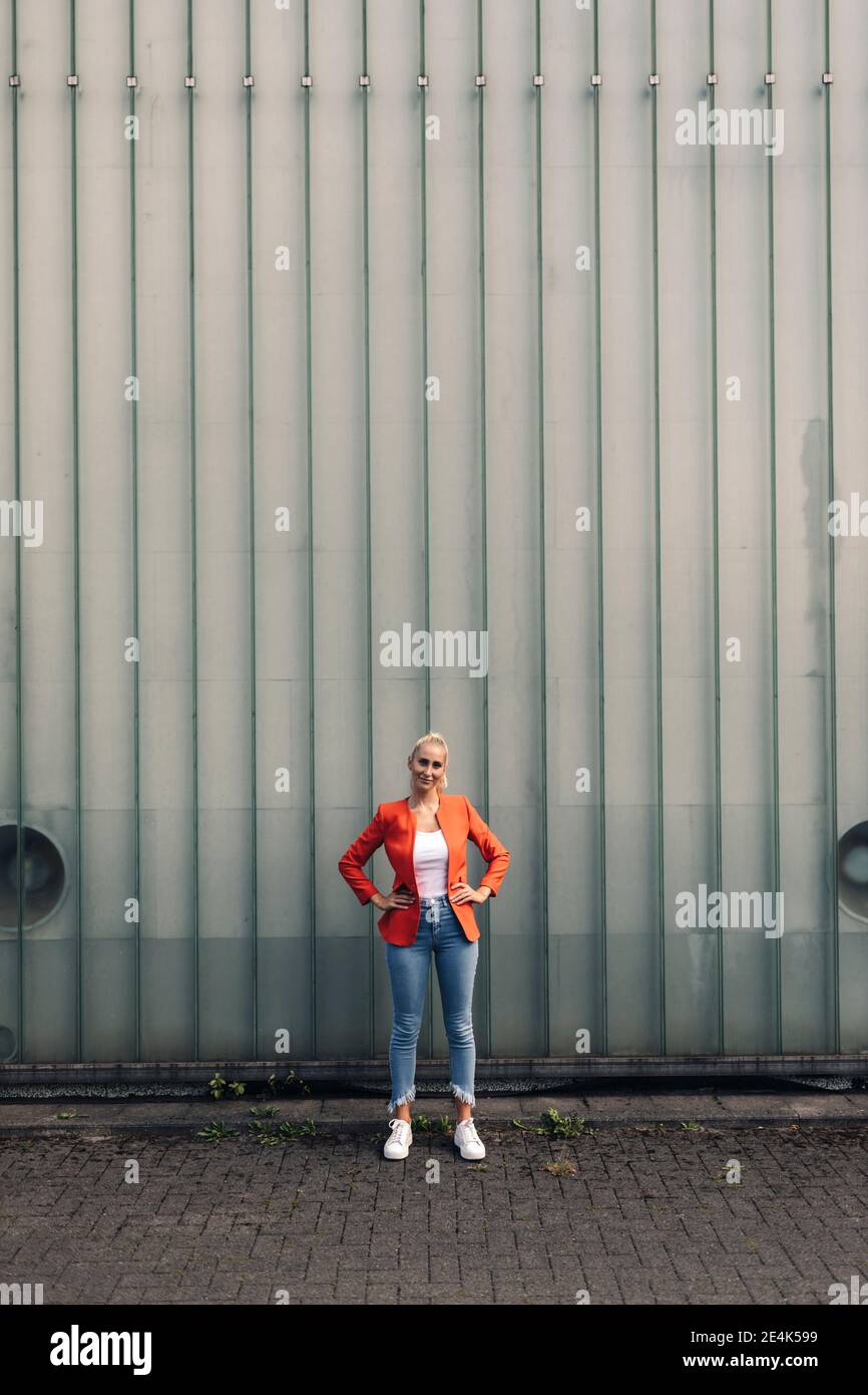 Donna imprenditore con mano sull'anca contro il muro Foto Stock