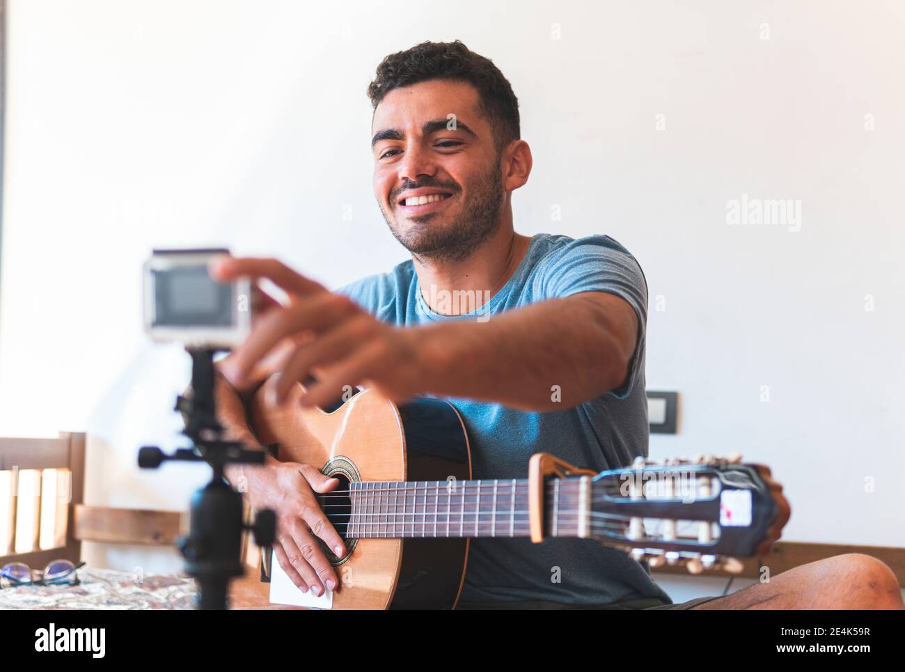 Sorridente musicista maschio che vlogging attraverso la macchina fotografica a casa Foto Stock