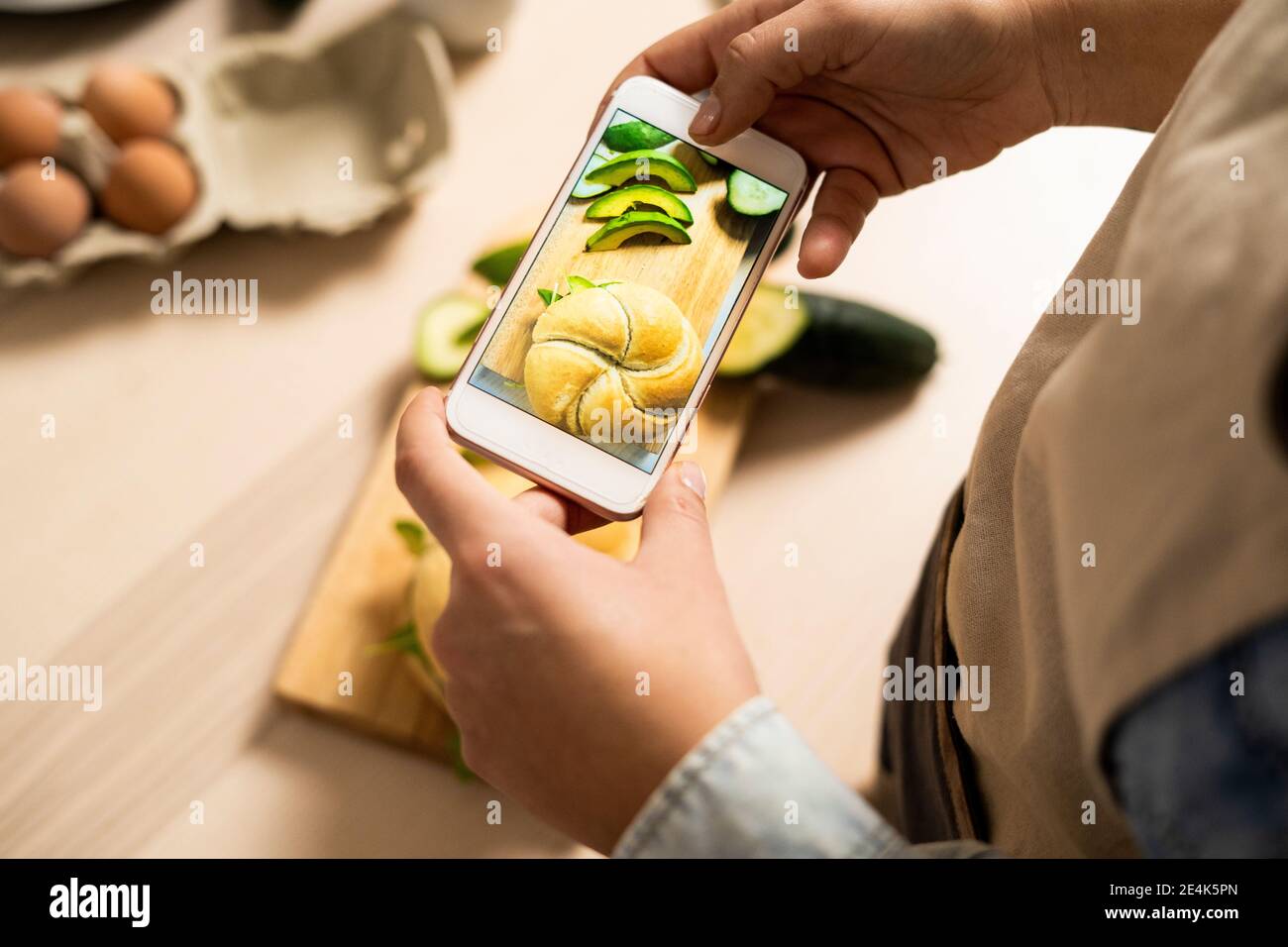 Mani di giovane donna che scattano foto del telefono intelligente di vegan sandwich Foto Stock