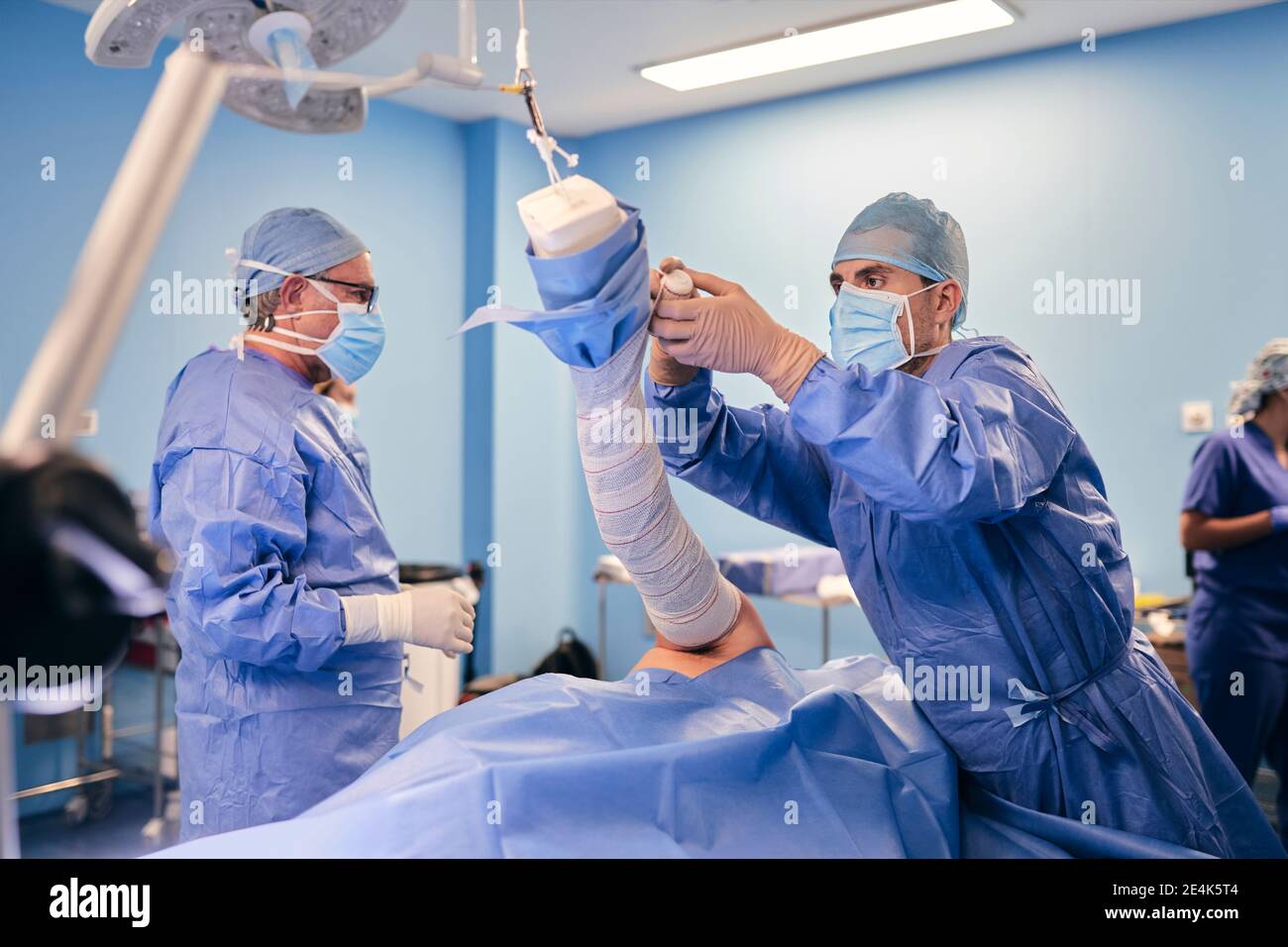 Medico che avvolge la mano mentre si sta con il collega in background a. sala operatoria Foto Stock