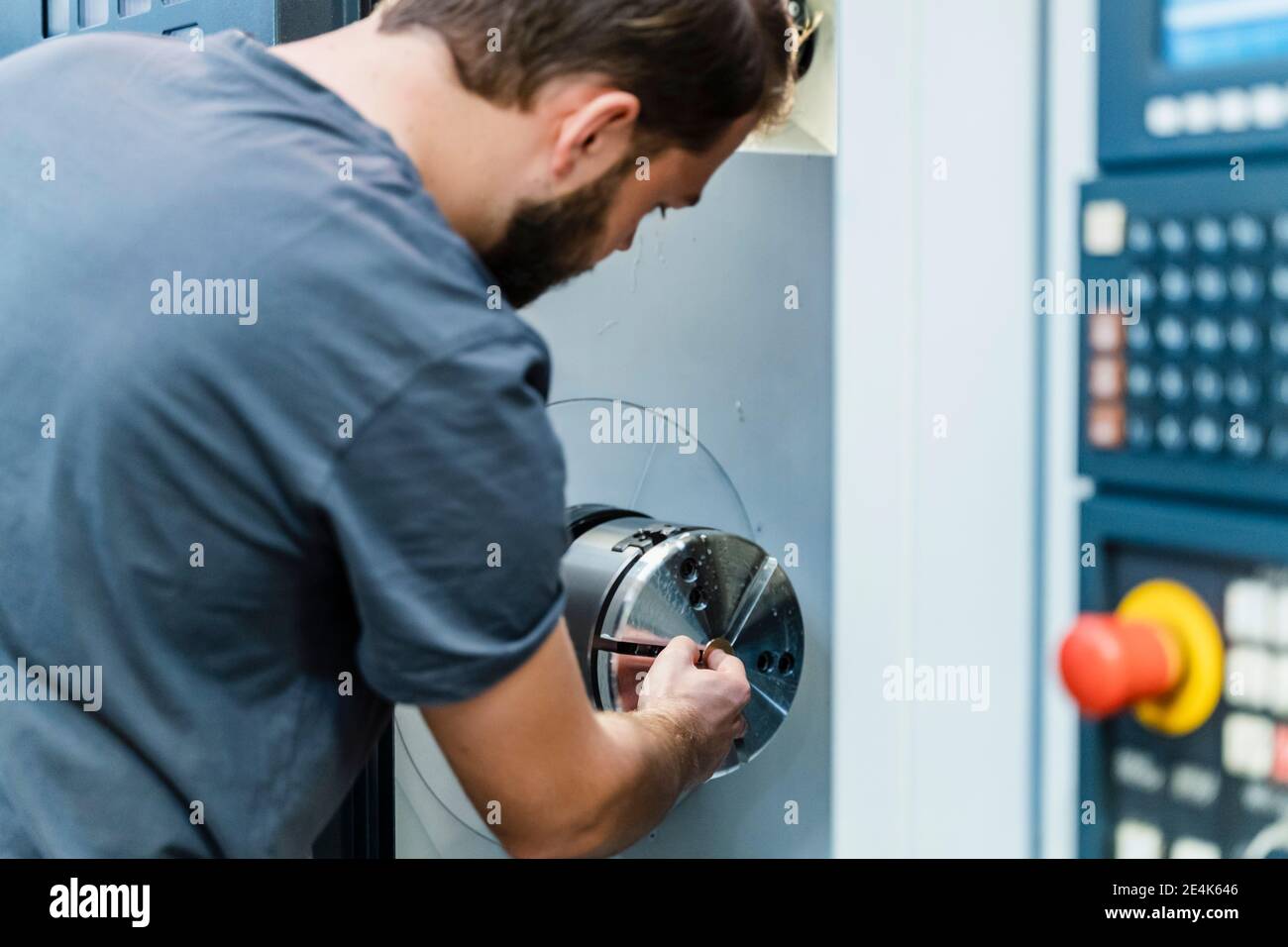 Addetto alla manutenzione che utilizza macchinari durante il lavoro in fabbrica Foto Stock
