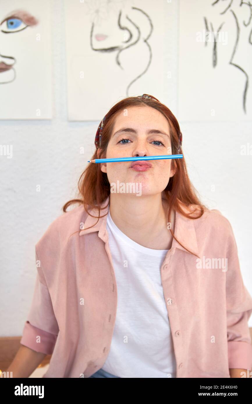 Artista femminile con matita sopra la bocca a casa Foto Stock