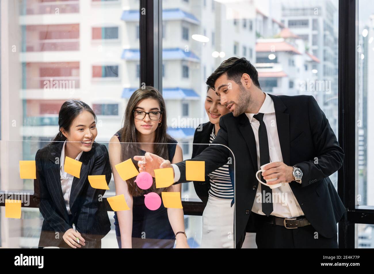 Team aziendale multietnico che si occupa di brainstorming con discutere a bordo moderno ufficio nel quartiere degli affari Foto Stock