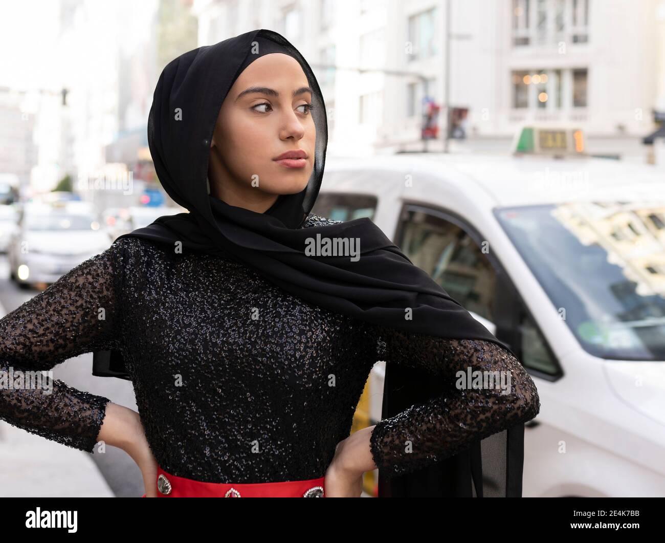 Ritratto di giovane bella donna che indossa hijab nero in posa via della città Foto Stock
