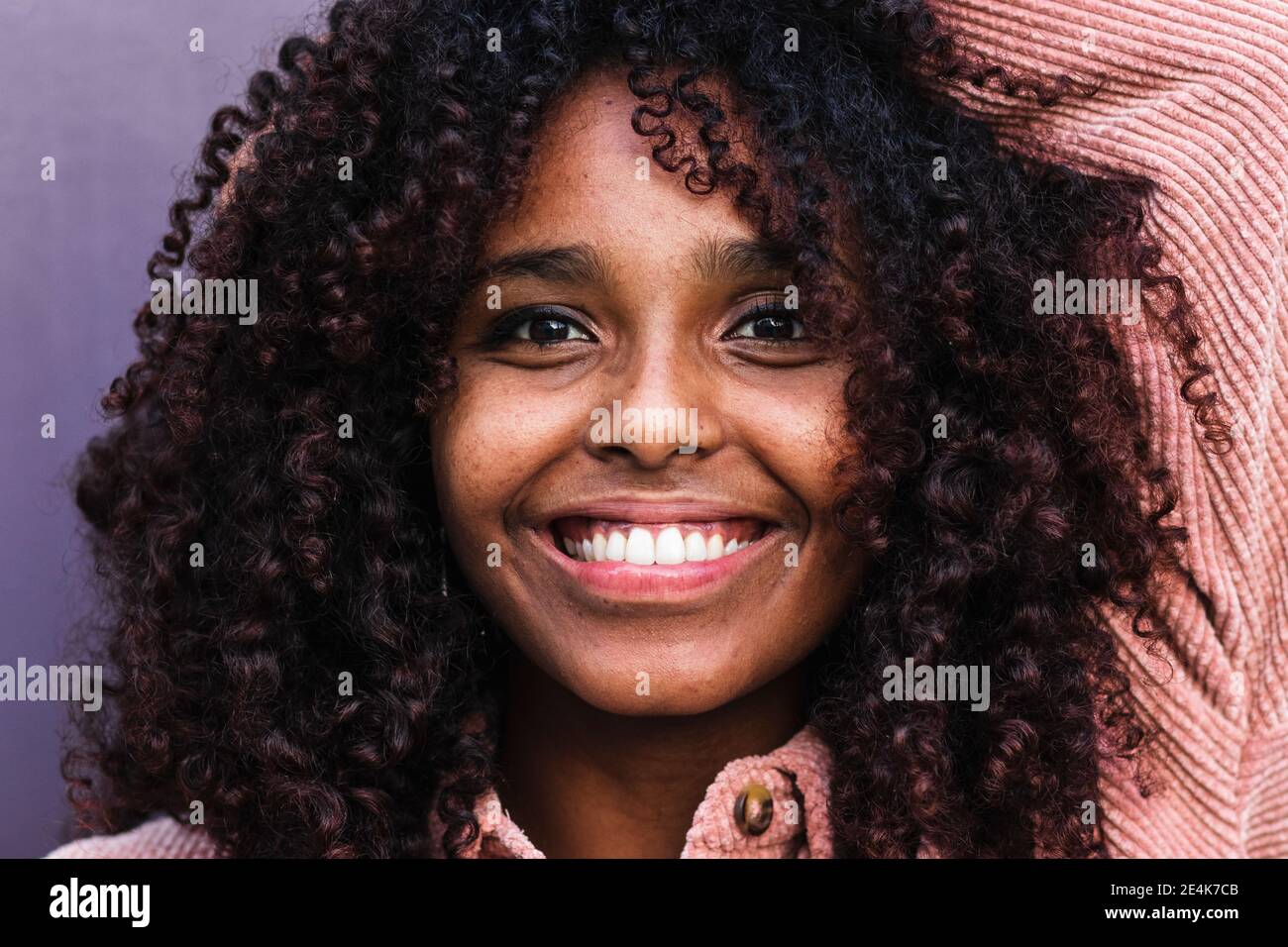Felice afro giovane donna con capelli ricci contro parete Foto Stock
