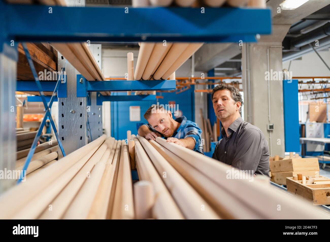 Due falegnami che esaminano i pali di legno nella sala di produzione Foto Stock