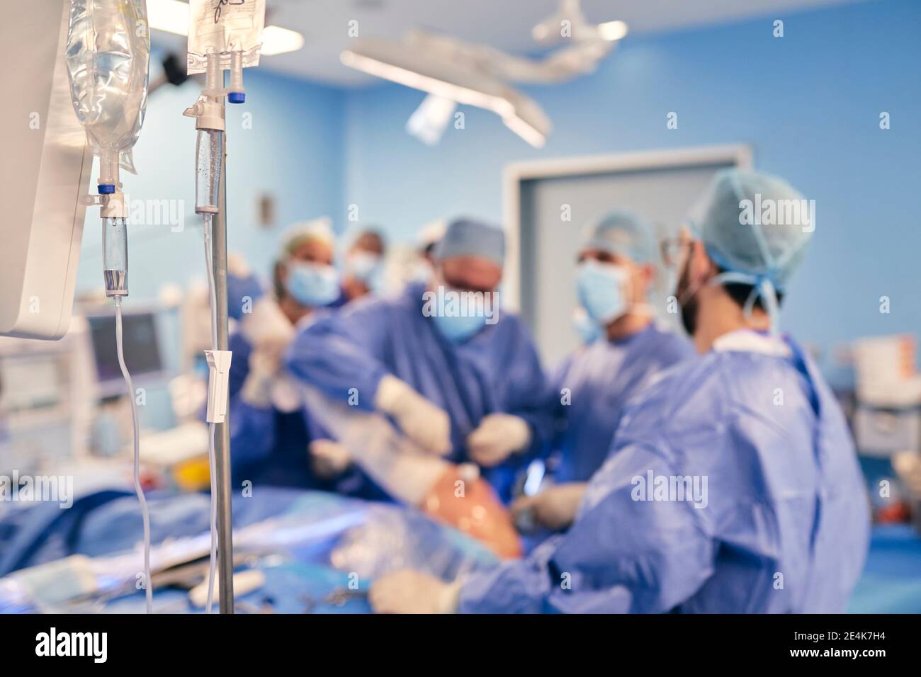 Infusione endovenosa in sala operatoria con medici in chirurgia operatoria sfondo Foto Stock