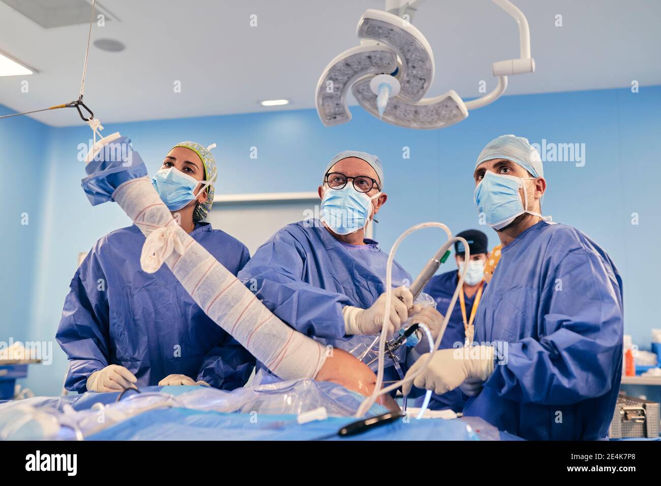 Medici che indossano maschera operatoria con apparecchiature endoscopiche wile in piedi in sala operatoria Foto Stock