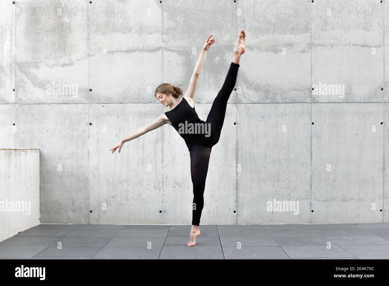 Ballerina in nero leotard danzante di fronte al muro di cemento Foto Stock